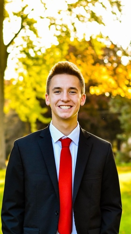Grant Luedtke in a black suit and red tie